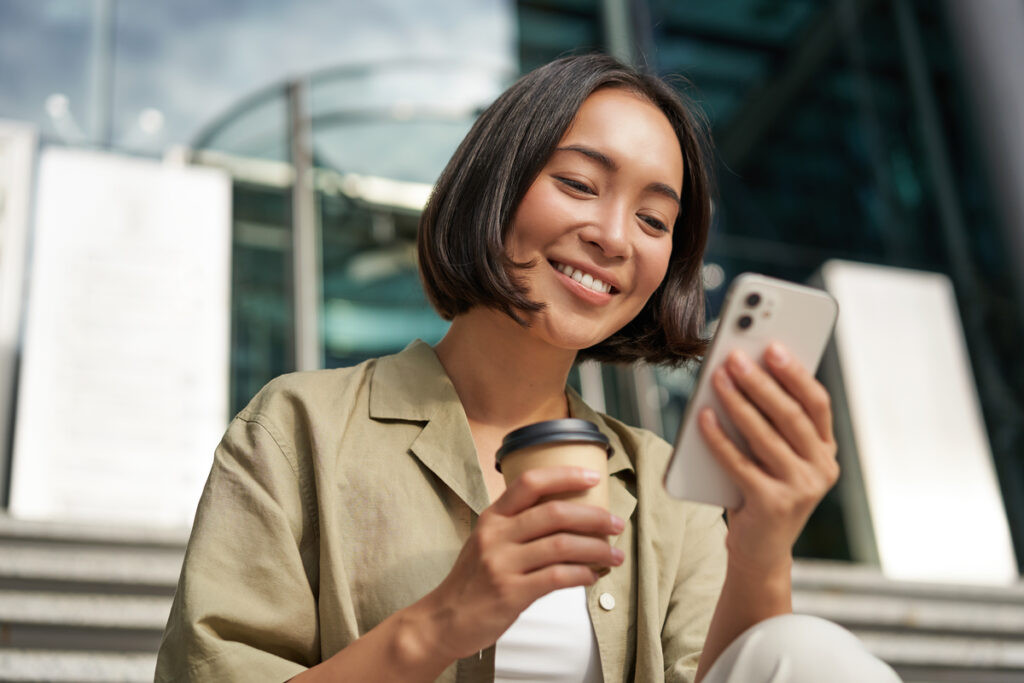 Người phụ nữ uống cà phê và sử dụng điện thoại di động