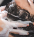 Một người thợ đang gội đầu cho khách hàng tại spa với bồn gội đầu hiện đại và ánh sáng dịu nhẹ