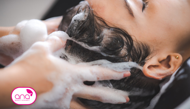 Một người thợ đang gội đầu cho khách hàng tại spa với bồn gội đầu hiện đại và ánh sáng dịu nhẹ