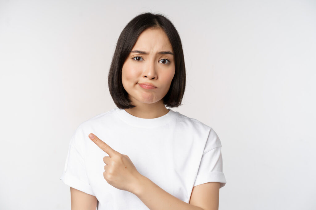 Cô gái châu Á hoài nghi chỉ vào logo sản phẩm với vẻ mặt thất vọng, không thích, phàn nàn